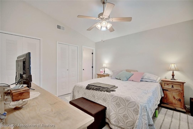 bedroom featuring ceiling fan, lofted ceiling, and two closets