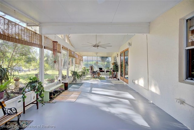 unfurnished sunroom featuring ceiling fan, plenty of natural light, and lofted ceiling with beams