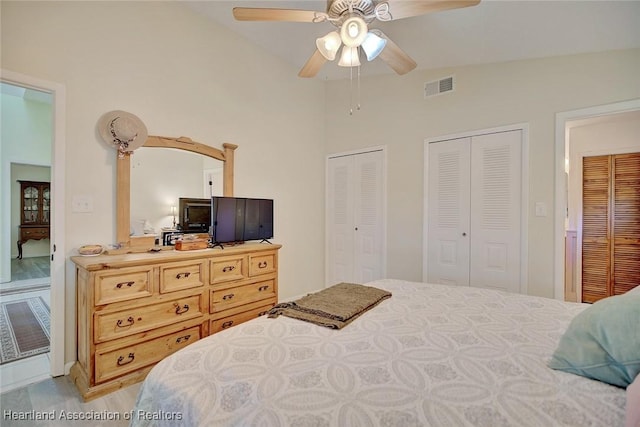 bedroom featuring vaulted ceiling, ceiling fan, and multiple closets