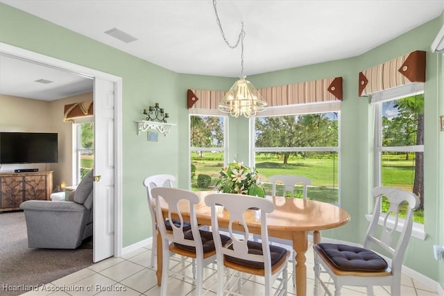 tiled dining area featuring a healthy amount of sunlight and a chandelier