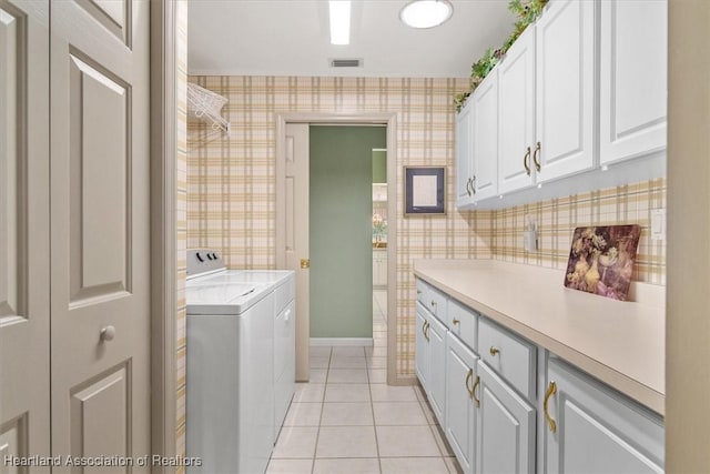 clothes washing area with light tile patterned floors, cabinets, and washer and dryer