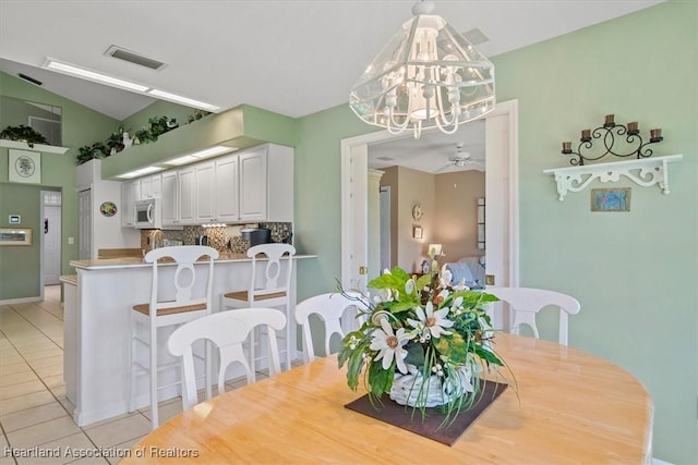 tiled dining area featuring vaulted ceiling and ceiling fan with notable chandelier