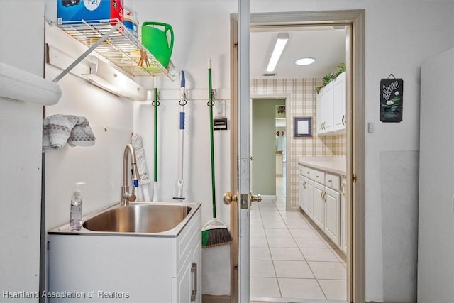 kitchen with white cabinetry, sink, and light tile patterned flooring