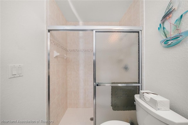 full bathroom featuring toilet, a textured wall, and a stall shower
