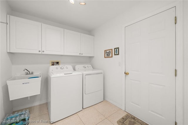 washroom with a sink, light tile patterned flooring, baseboards, washer and dryer, and cabinet space