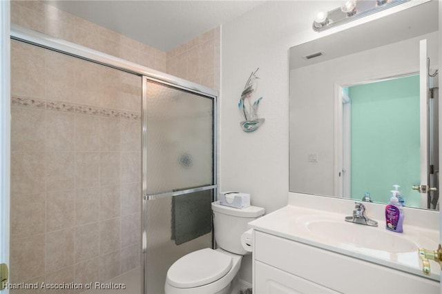 bathroom with visible vents, toilet, vanity, and a stall shower