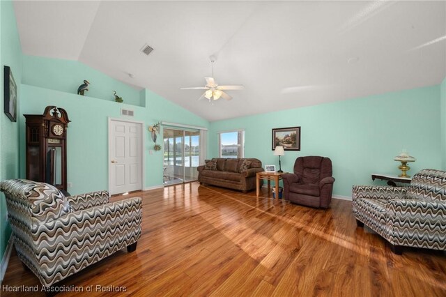 living room with ceiling fan, lofted ceiling, wood finished floors, and visible vents