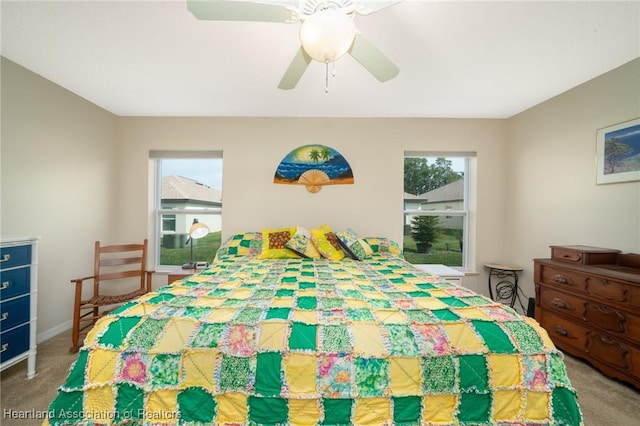 carpeted bedroom featuring multiple windows and ceiling fan