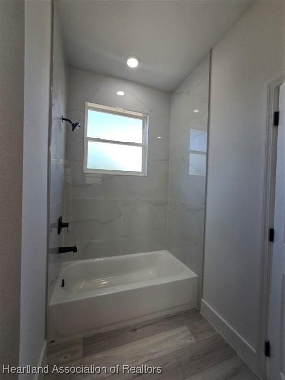 bathroom with hardwood / wood-style flooring and tiled shower / bath