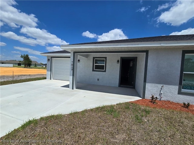 exterior space with stucco siding, concrete driveway, and an attached garage