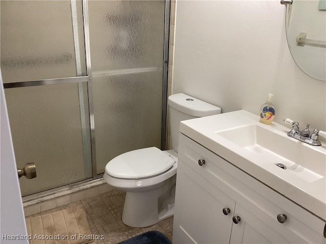 bathroom featuring vanity, toilet, and a shower with door