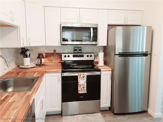 200 Robin Ave, Sebring, FL 33870 - kitchen with stainless steel appliances, butcher block countertops, a sink, backsplash, and white cabinets
