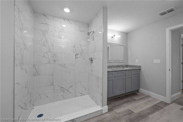 bathroom featuring tiled shower, wood-type flooring, vanity, and a textured ceiling