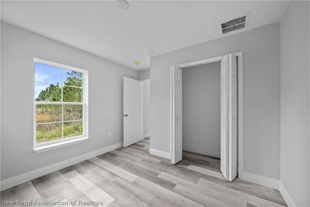 unfurnished bedroom featuring multiple windows and light hardwood / wood-style floors