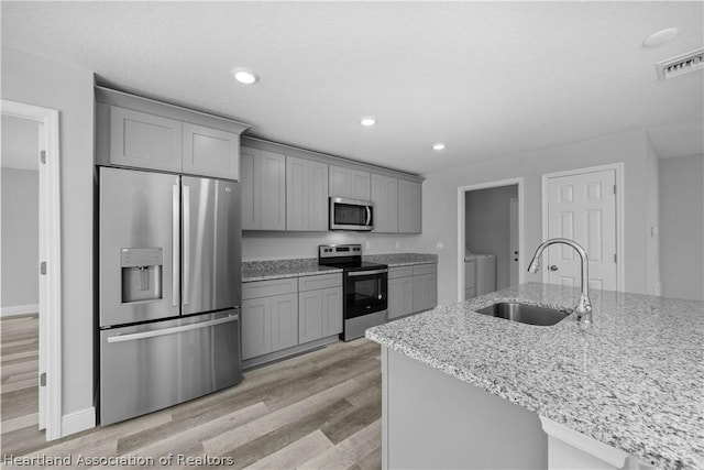 kitchen featuring light stone countertops, stainless steel appliances, gray cabinetry, and sink