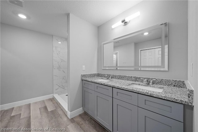 bathroom featuring a tile shower, hardwood / wood-style floors, vanity, and a textured ceiling