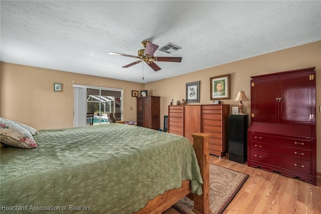 bedroom with ceiling fan, light hardwood / wood-style floors, a textured ceiling, and access to outside