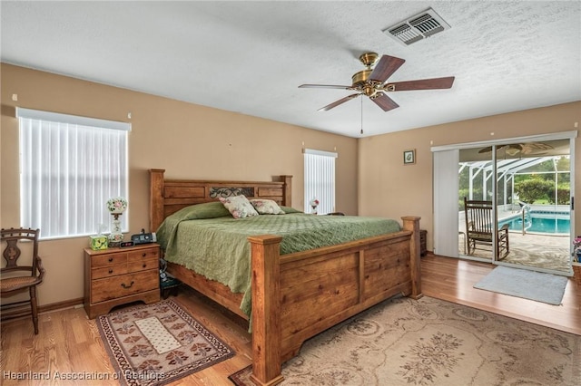 bedroom featuring access to exterior, hardwood / wood-style floors, multiple windows, and ceiling fan