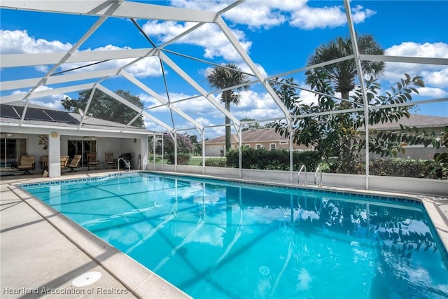 view of pool featuring glass enclosure and a patio area