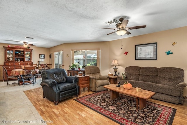 living room with a textured ceiling, light hardwood / wood-style floors, and ceiling fan