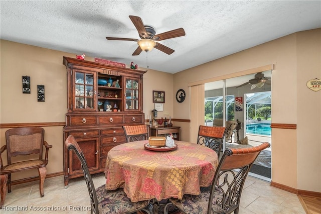 tiled dining area with ceiling fan and a textured ceiling