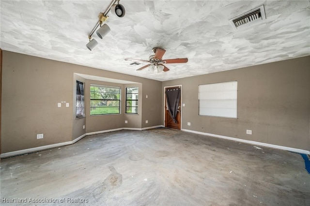 empty room featuring concrete flooring, rail lighting, and ceiling fan