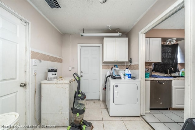 washroom featuring sink, a textured ceiling, washer / dryer, light tile patterned floors, and tile walls