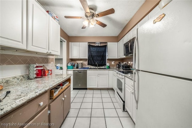 kitchen featuring light stone counters, sink, white cabinets, and white appliances