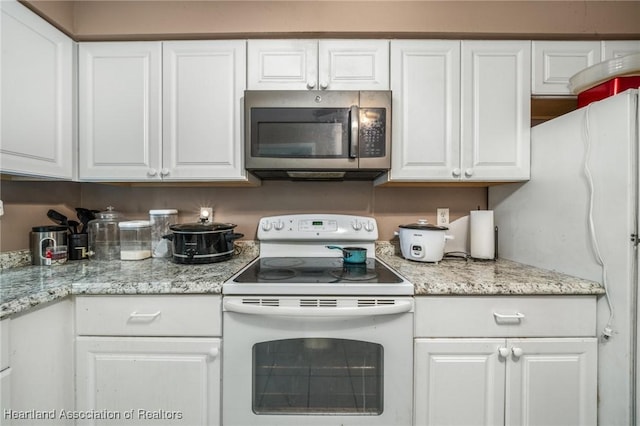 kitchen with white cabinetry, light stone countertops, and white appliances