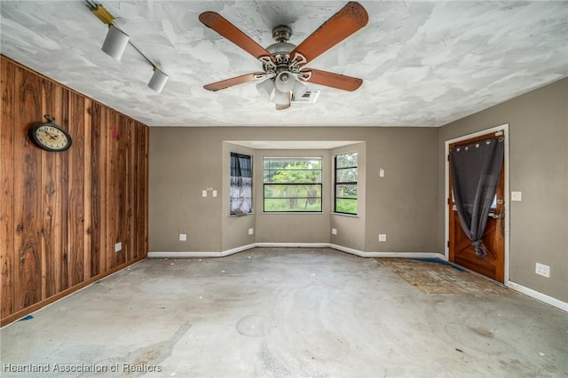 empty room with ceiling fan and wood walls