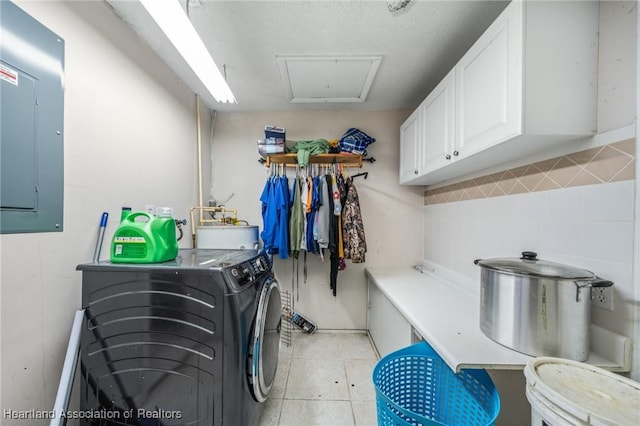 clothes washing area featuring cabinets, sink, washing machine and clothes dryer, electric panel, and light tile patterned flooring