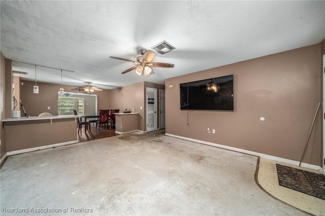 unfurnished living room with ceiling fan, concrete floors, and a textured ceiling