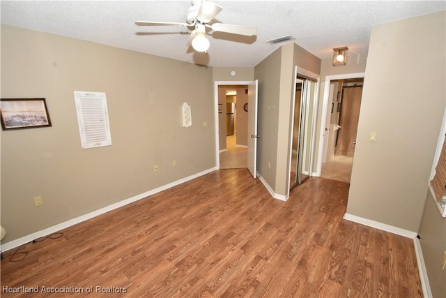 unfurnished room with ceiling fan, hardwood / wood-style flooring, and a textured ceiling