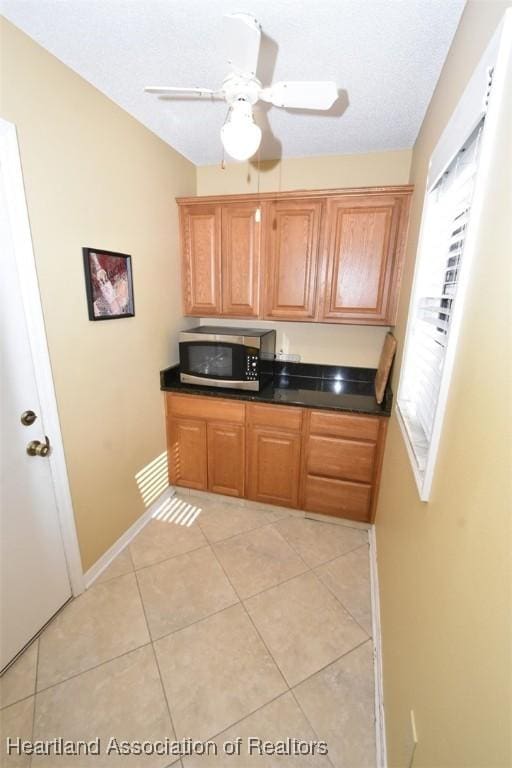 kitchen with ceiling fan, a textured ceiling, and light tile patterned floors