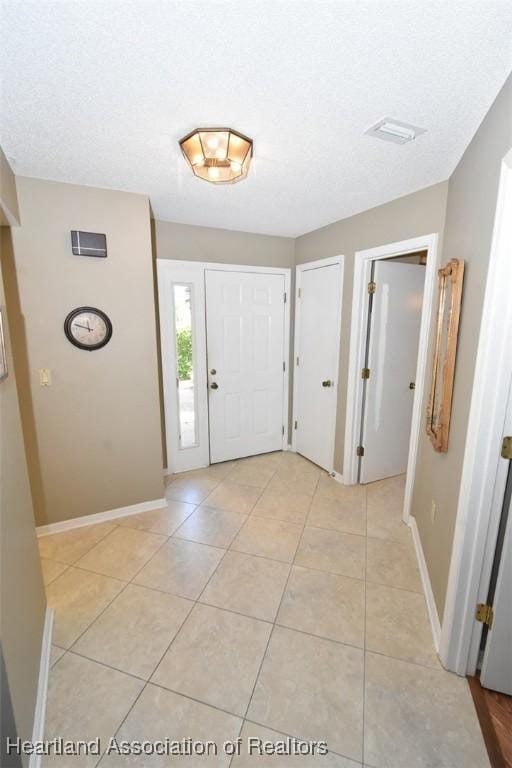 entryway with a textured ceiling and light tile patterned floors