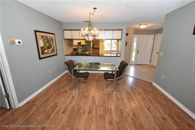 dining space with hardwood / wood-style floors, a textured ceiling, and a chandelier