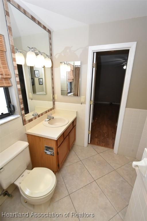 bathroom featuring tile patterned floors, toilet, tile walls, and vanity