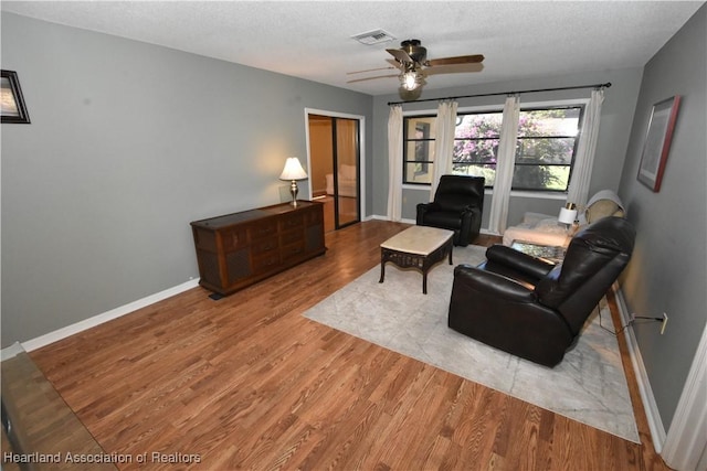 living room featuring a textured ceiling, light hardwood / wood-style floors, and ceiling fan