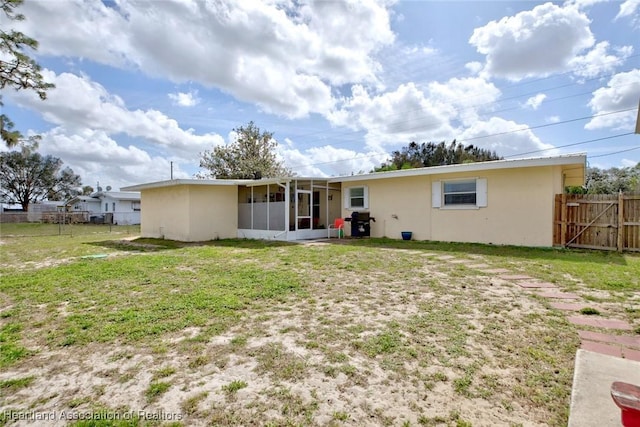 back of property with a sunroom, fence, and a yard