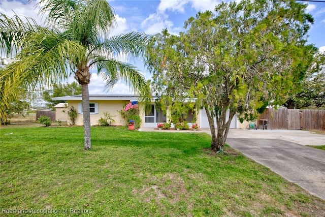 view of front of home featuring a garage, fence, driveway, stucco siding, and a front lawn