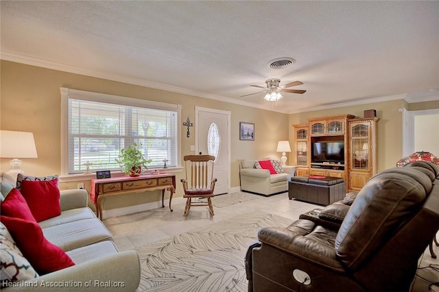 living room featuring light tile patterned flooring, a ceiling fan, visible vents, baseboards, and ornamental molding