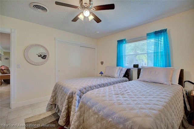 bedroom featuring ceiling fan, light tile patterned flooring, visible vents, baseboards, and a closet