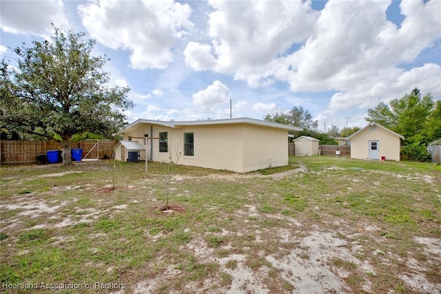 back of house featuring an outbuilding, stucco siding, a fenced backyard, and a shed