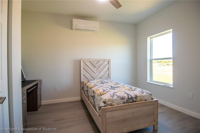 bedroom featuring an AC wall unit, wood finished floors, baseboards, and ceiling fan