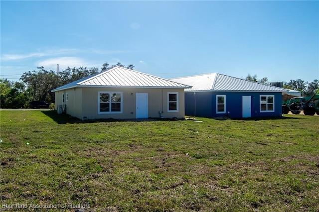 back of property featuring a standing seam roof, a lawn, and metal roof