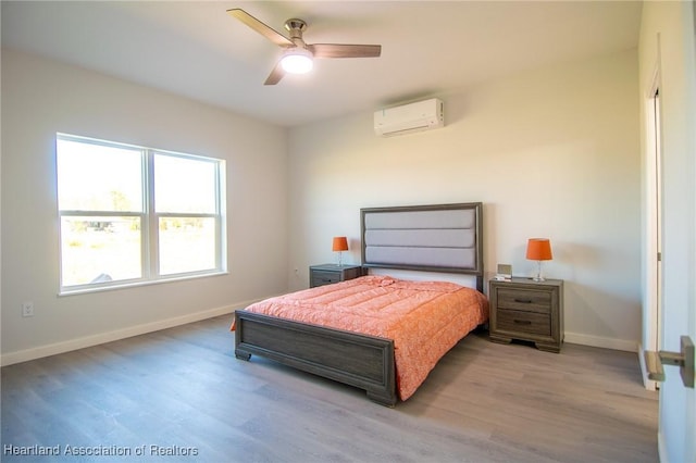 bedroom featuring ceiling fan, baseboards, an AC wall unit, and wood finished floors