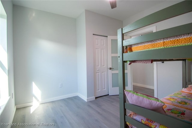 unfurnished bedroom featuring ceiling fan, a closet, baseboards, and wood finished floors