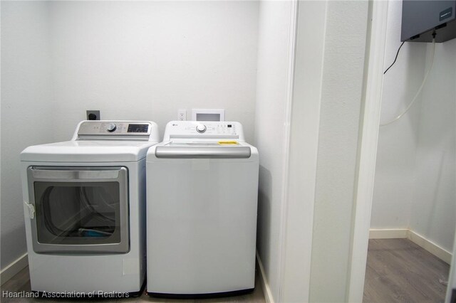 laundry room featuring baseboards, wood finished floors, and washer and clothes dryer