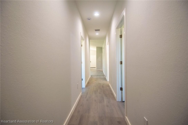 hallway with visible vents, wood finished floors, and baseboards