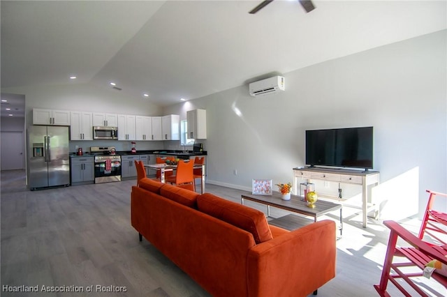 living room featuring baseboards, a wall mounted AC, lofted ceiling, and wood finished floors